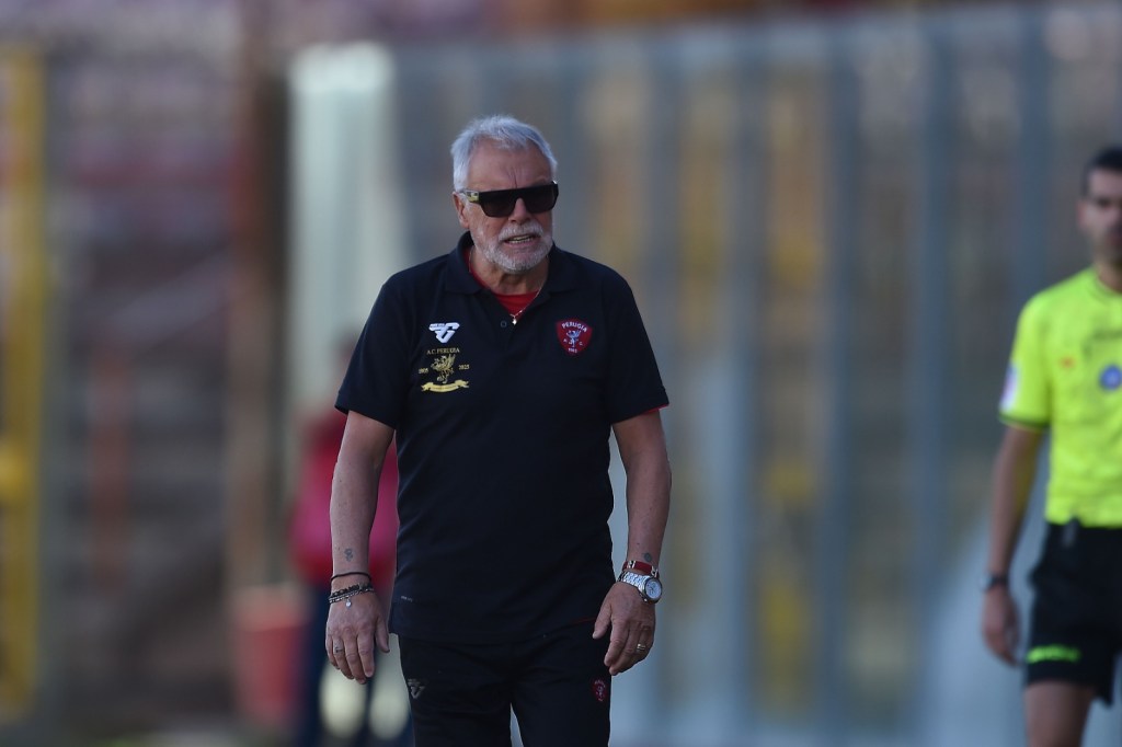 Un allenatore della squadra di calcio Perugia cammina in campo indossando occhiali da sole.