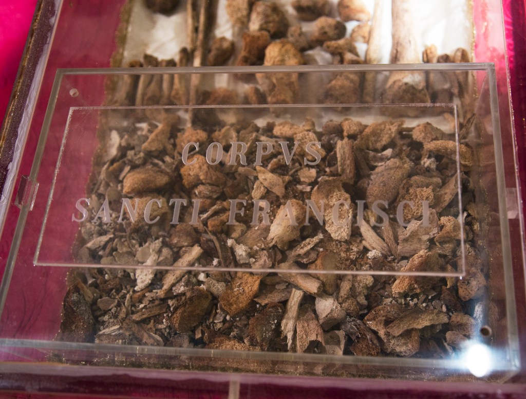 Resto mortale di San Francesco conservato in una teca di vetro con incisione 'CORPUS SANCTI FRANCISCI'.