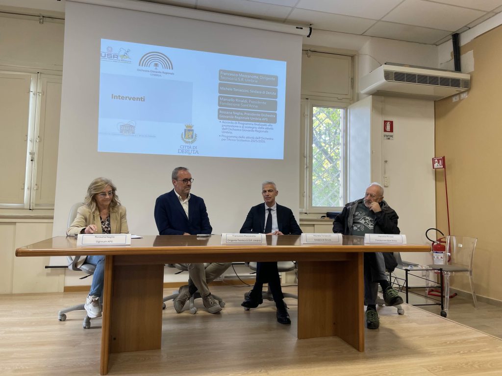 Un incontro di presentazione dell'accordo per l'Orchestra Giovanile Regionale dell'Umbria, con relatori seduti attorno a un tavolo in una sala conferenze.