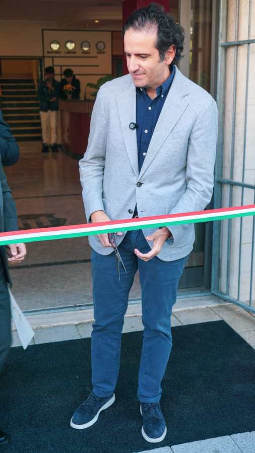 Inaugurazione dell'Housing Tirrenus a Montebello, con una persona che tiene le forbici per tagliare un nastro tricolore.