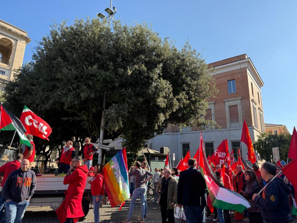 Manifestazione a Terni con partecipanti che sventolano bandiere della CGIL e della Palestina, sotto un grande albero.
