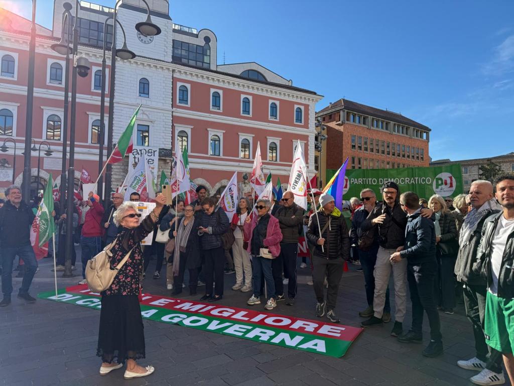 Una folla di manifestanti in piazza della Repubblica a Terni, con striscioni e bandiere, durante una protesta per chiedere le dimissioni del sindaco.