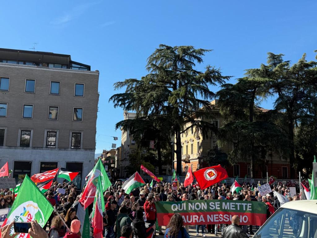 Una grande folla si raduna in piazza della Repubblica a Terni per protestare contro il sindaco, con cartelli e bandiere rosso-verdi.