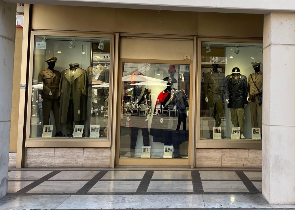Vetrina di un negozio con uniformi storiche e operative esposte, incluse giacche e cappelli, in occasione delle celebrazioni del 4 novembre a Terni.