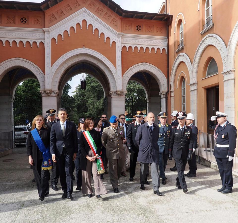 Rappresentanti delle istituzioni civili e militari partecipano a una cerimonia commemorativa presso un cimitero, con la sindaca e altri ufficiali tra i presenti.