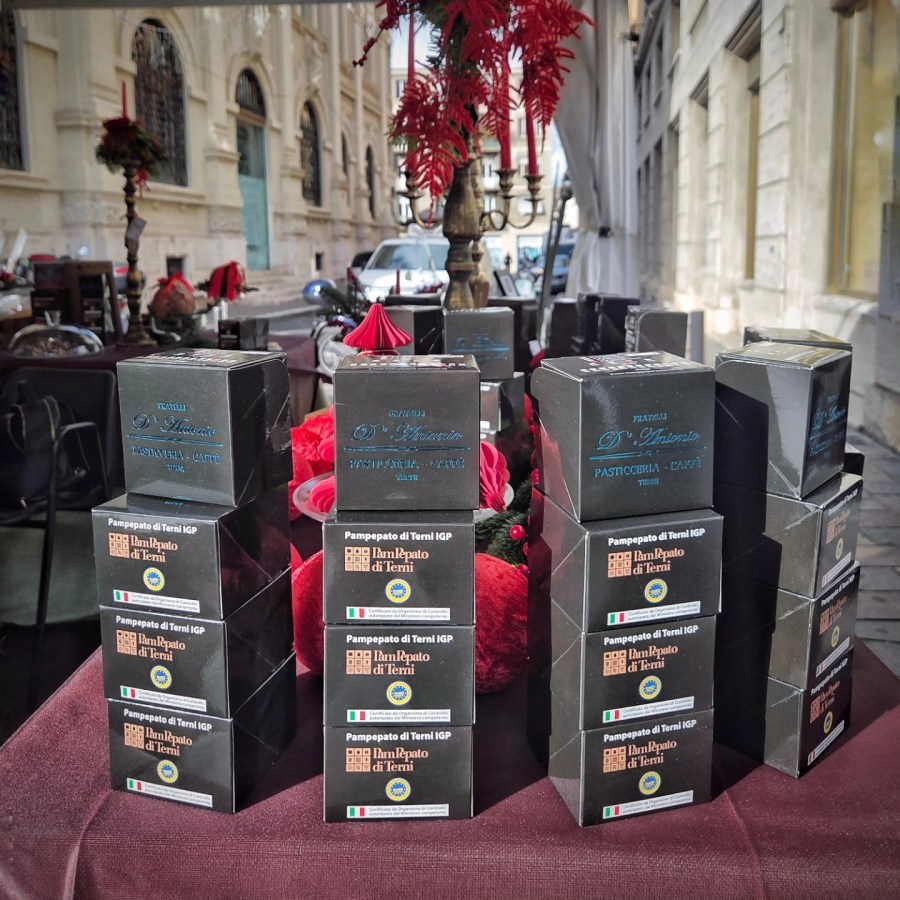 A display of packaged Panpepato di Terni IGP, a traditional Italian cake, arranged on a table, surrounded by festive decorations.