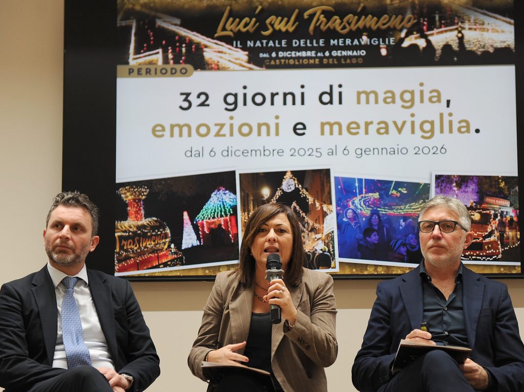 Presentazione dell'evento 'Luci sul Trasimeno' con tre relatori seduti davanti a un grande schermo che annuncia un Natale di emozioni e meraviglia dal 6 dicembre 2025 al 6 gennaio 2026.