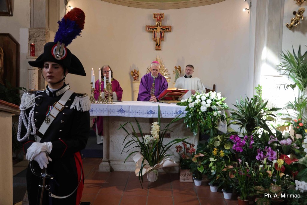 A solemn church service taking place, featuring a priest and two others at the altar, with a guard in a formal military uniform standing in the foreground.