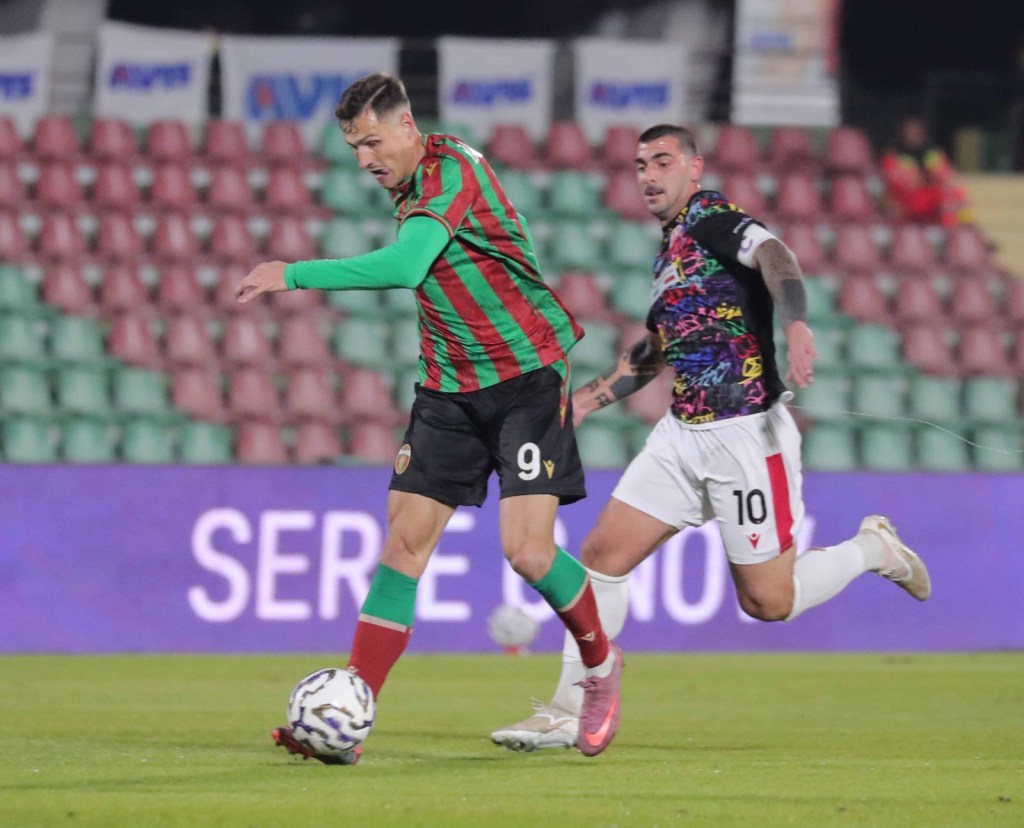 Un giocatore della Ternana in maglia verde e rossa in azione sul campo, mentre un avversario della Vis Pesaro lo insegue.