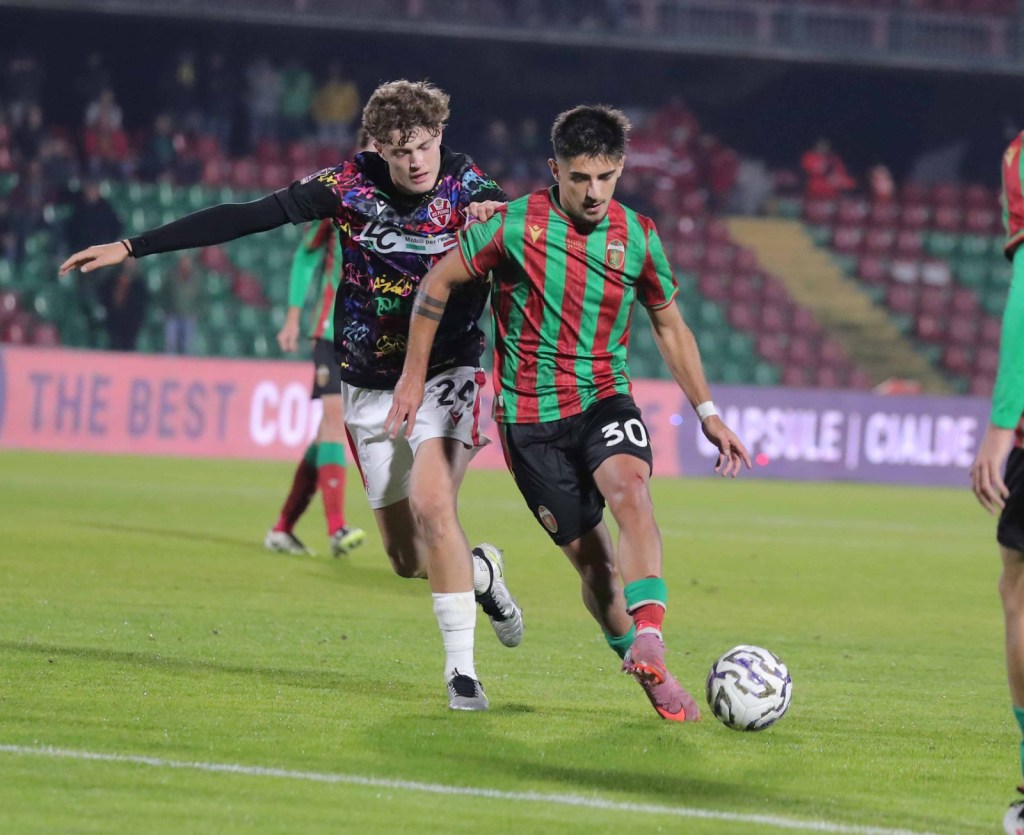 Un giocatore della Ternana con maglia rossa e verde dribbla un avversario della Vis Pesaro in campo, durante una partita di calcio.
