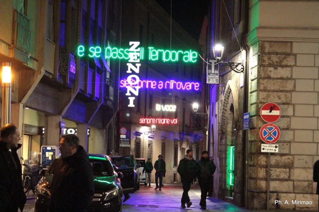 Una strada di città illuminata da insegne al neon notturne in un ambiente urbano.