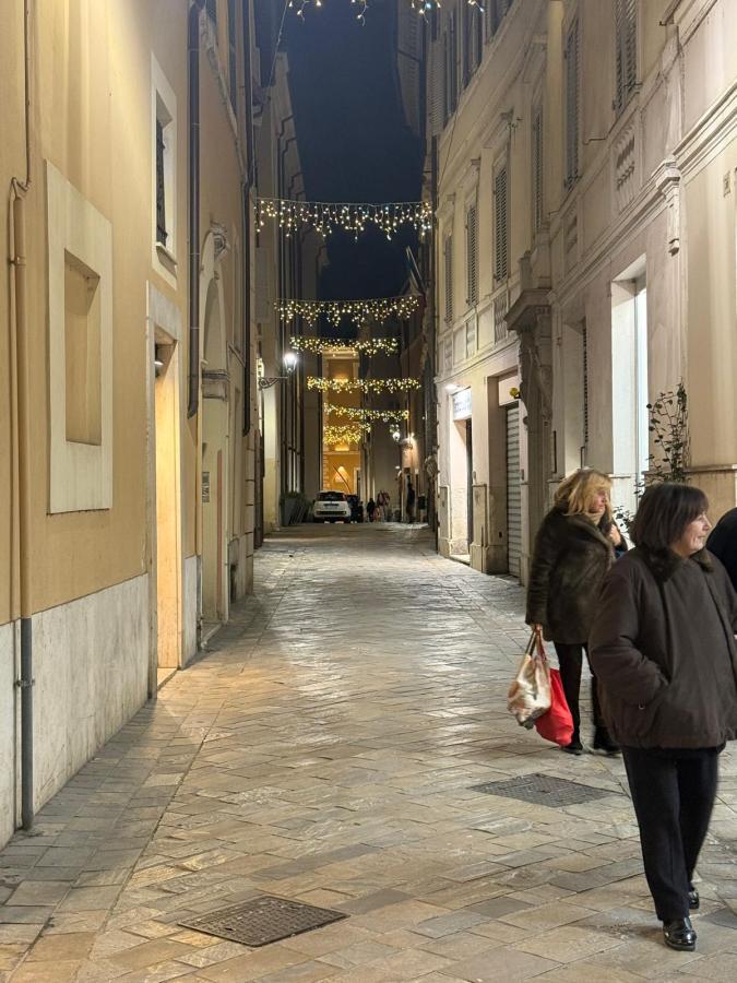 A narrow alleyway illuminated with decorative lights during nighttime, featuring two women walking along the cobblestone path beside historic buildings.