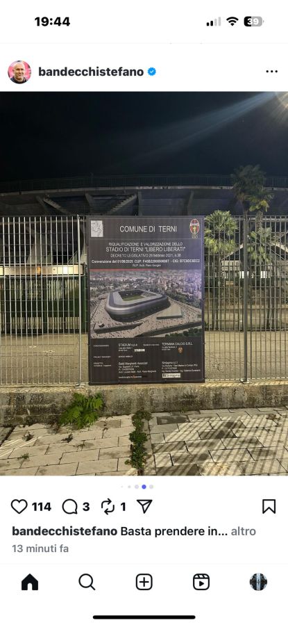 Un cartello che descrive il progetto di ristrutturazione dello stadio di Terni, visibile di notte con un'illuminazione artificiale. Il cartello reca il titolo 'COMUNE DITERNI' e dettagli sul progetto, accompagnato da un'immagine del futuro stadio.