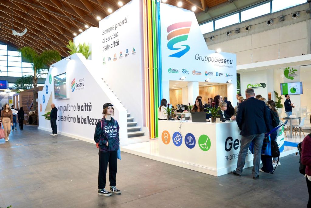 Stand del Gruppo Gesenu all'Ecomondo 2025, con visitatori che interagiscono e informazioni sulla sostenibilità sullo sfondo.