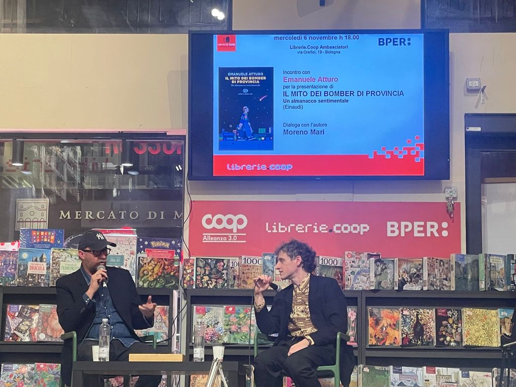 Authors Emanuele Atturo and Moreno Mari discussing the book 'Il Mito Dei Bomber Di Provincia' during a presentation event at Libreria Coop Ambasaditori in Bologna.