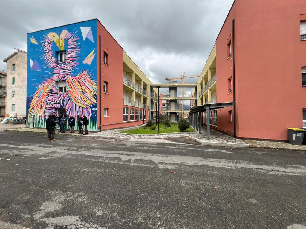 Murales colorato intitolato 'GRAFFAUNE AMOUR' realizzato dall'artista DACO, che rappresenta una coppia di cigni con colli intrecciati a formare un cuore, situato in un'area urbana a Terni.