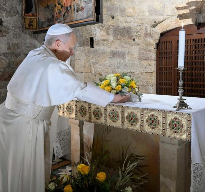Il Papa Leone XIV depone un mazzo di fiori su un altare durante un momento di preghiera in un luogo sacro.