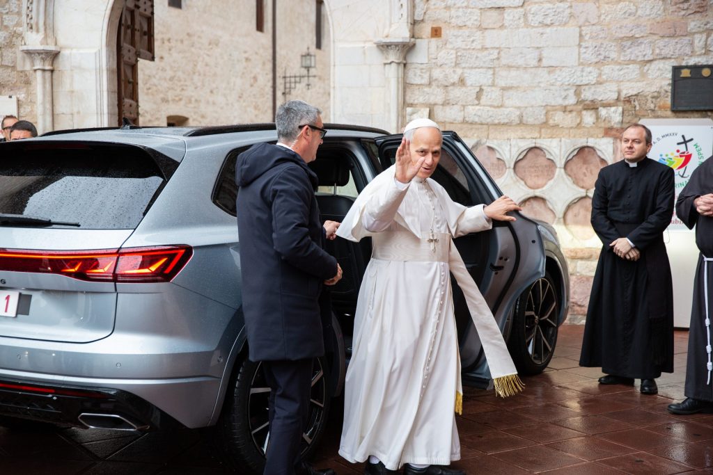 Il Papa Leone XIV saluta mentre scende da un'auto in una giornata piovosa a Santa Maria degli Angeli, Assisi.