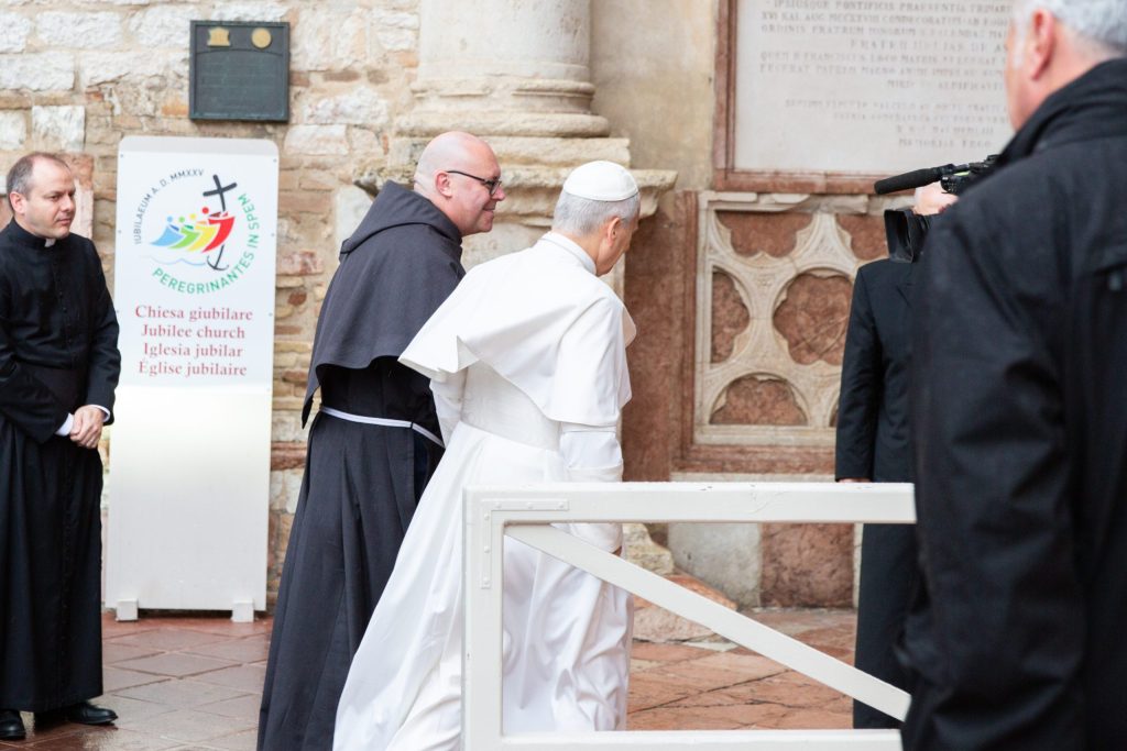 Il Papa Leone XIV in visita alla Chiesa giubilare di Santa Maria degli Angeli ad Assisi, accolto da frati e fedeli.