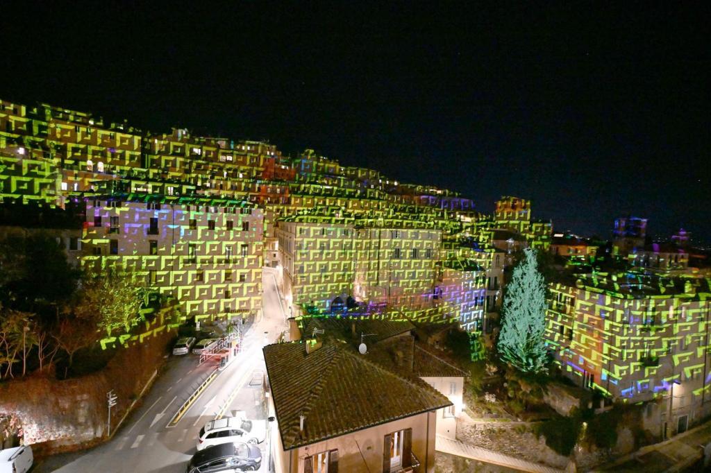 Proiezione luminosa su edifici di Perugia durante l'evento di Natale 2025, con colori vivaci e motivi geometrici che decorano le facciate storiche.