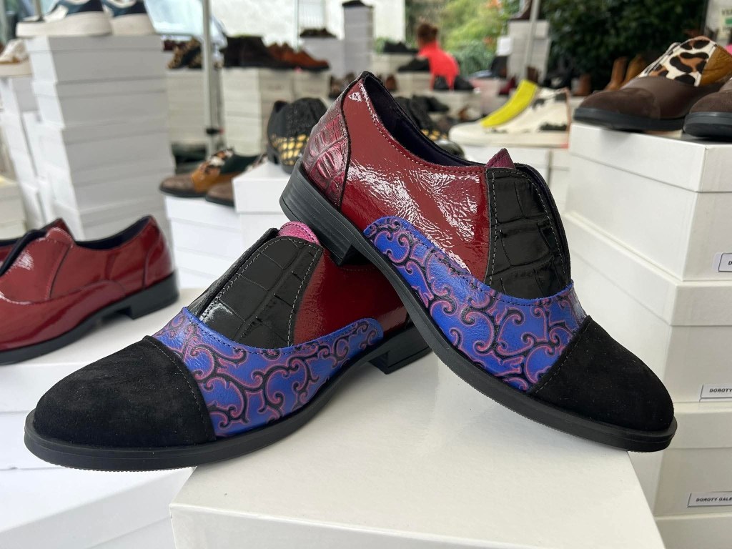 Scarpe eleganti con dettagli colorati su uno sfondo di scatole bianche.