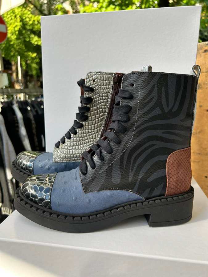 Stivali colorati con diverse texture e materiali, esposti su una superficie bianca, immersi in un mercato all'aperto.