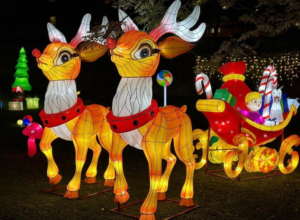 Due renne luminose colorate con una slitta decorativa sullo sfondo, immersi in un'atmosfera festiva.