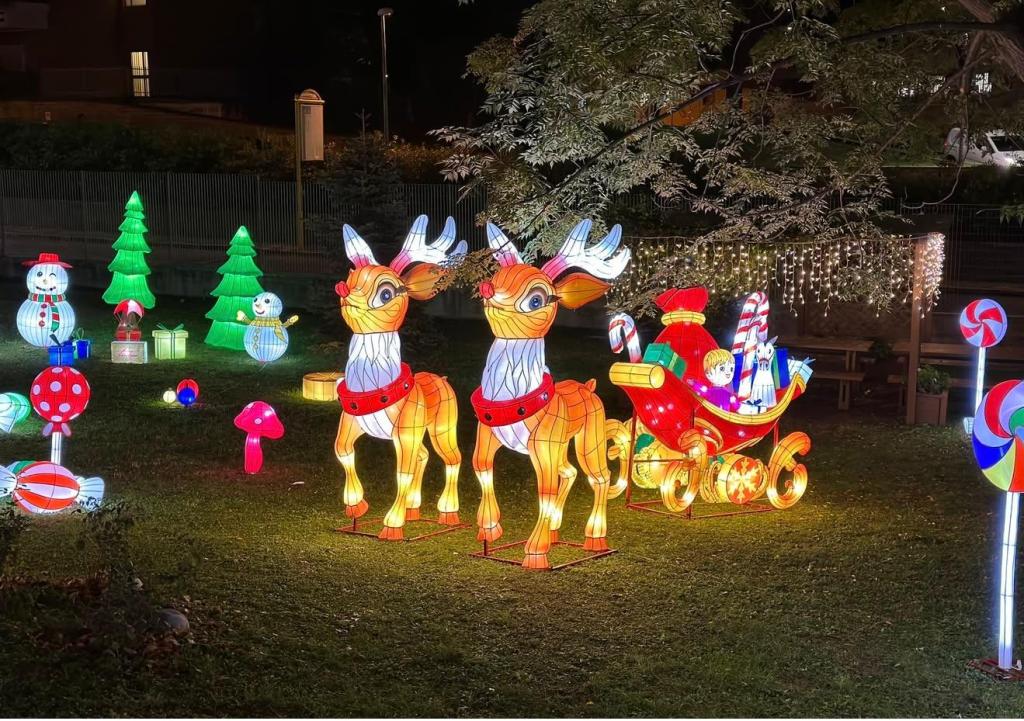 Installazioni luminose festive con renne, slitta di Babbo Natale, pupazzo di neve e alberi di Natale nel campus universitario.