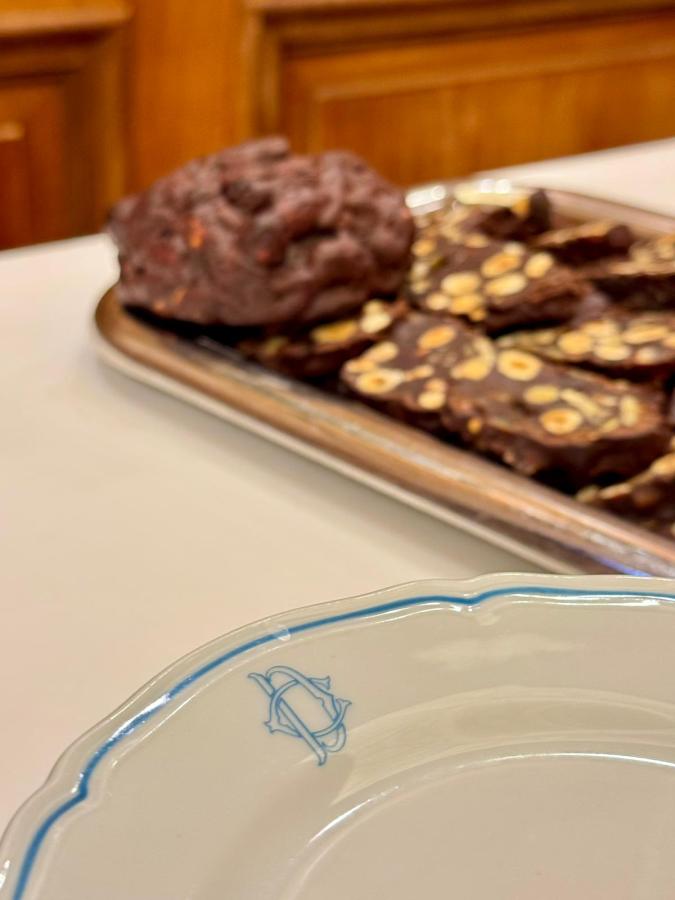 A close-up of a decorative plate with a blue design, featuring a platter of dark chocolate treats and cookies in the background, set on a table.