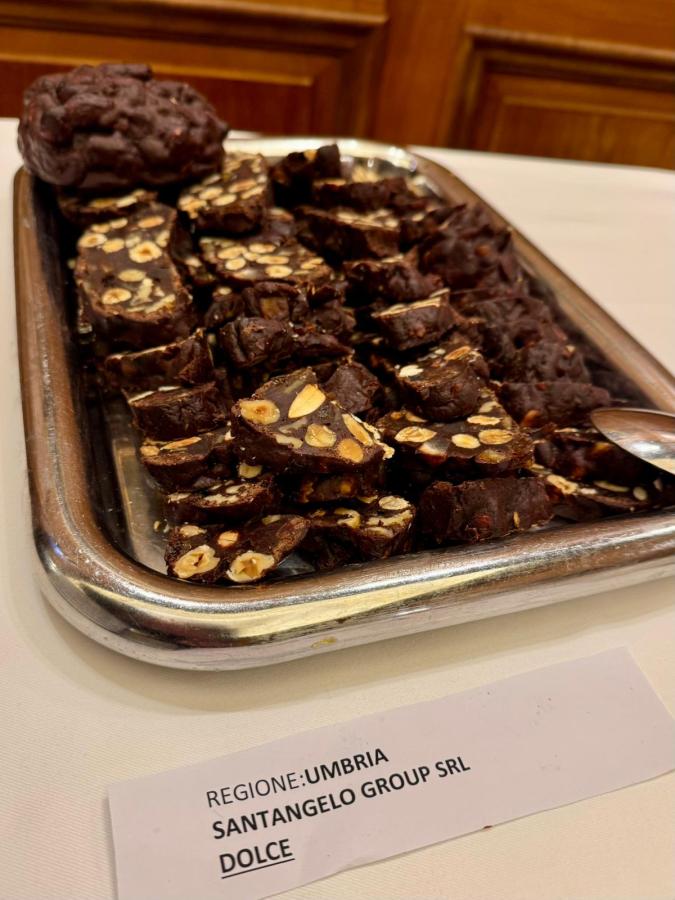 A platter displaying slices of chocolate nougat with almonds, labeled with 'REGIONE: UMBRIA, SANTANGELO GROUP SRL, DOLCE'.
