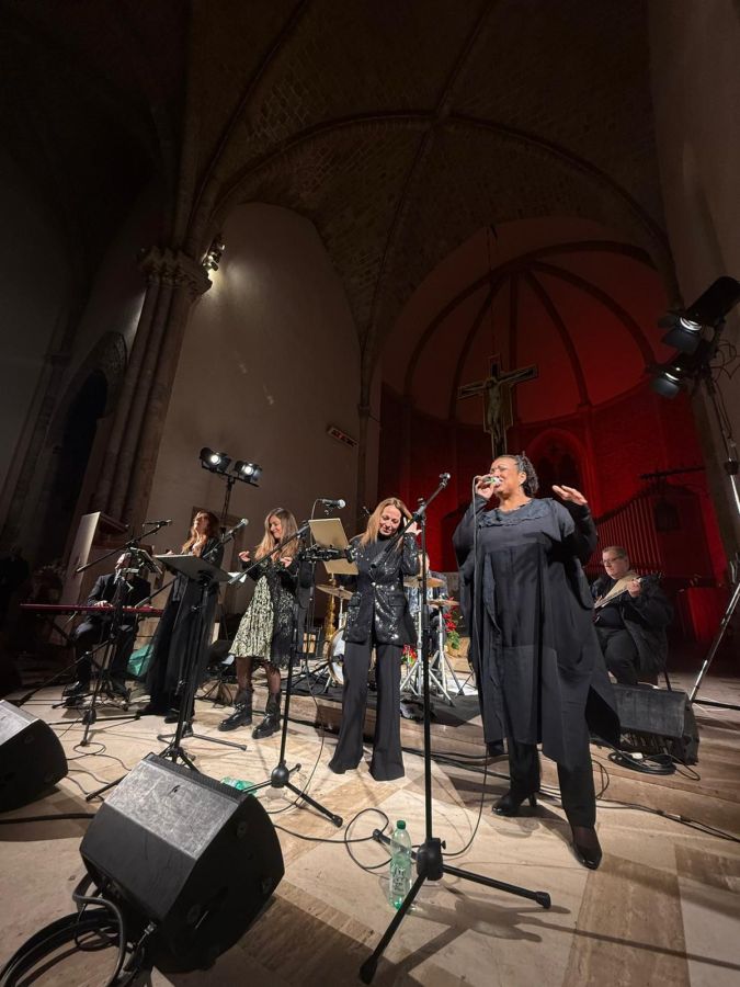 Concerto Gospel con una band di artisti sul palco, che si esibiscono in una chiesa con un'atmosfera suggestiva.