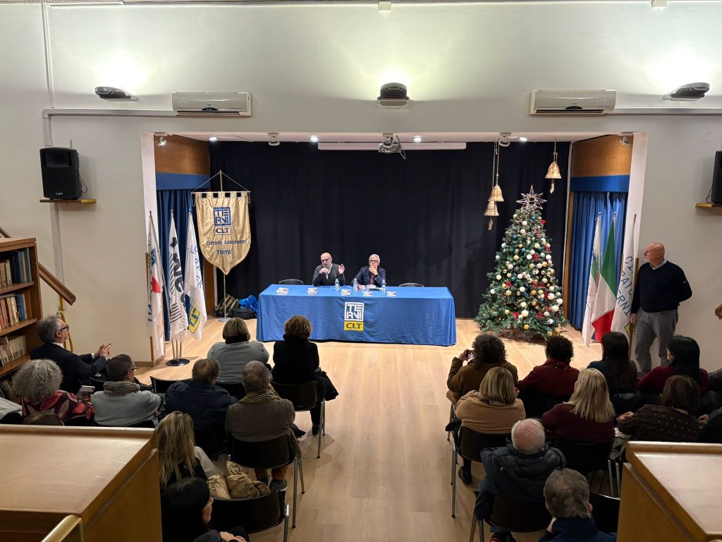 Un incontro di presentazione del libro 'Pensieri nell’acqua' di Franco Fogliano, con un pubblico attento e una decorazione natalizia sullo sfondo.