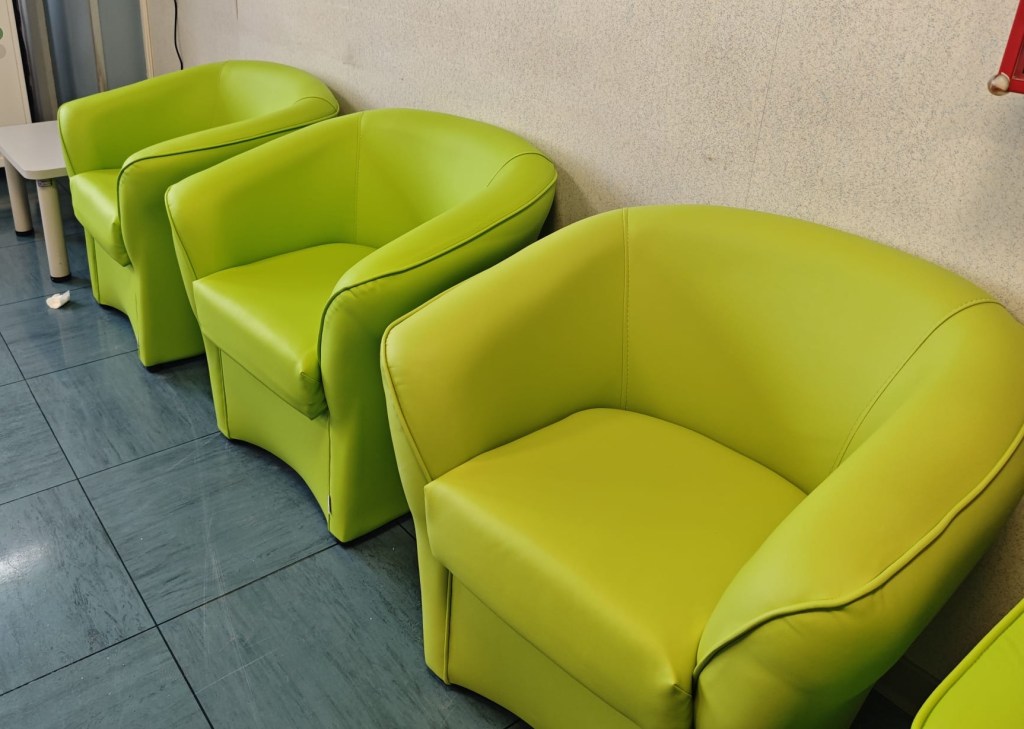 Tre poltrone in ecopelle verde disposte nella sala di attesa di Oncologia.
