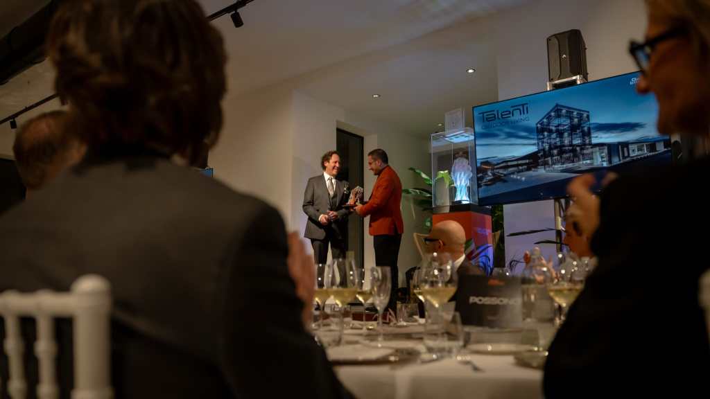 Evento di gala in corso presso il showroom Talenti, con ospiti che assistono alla consegna di un premio.