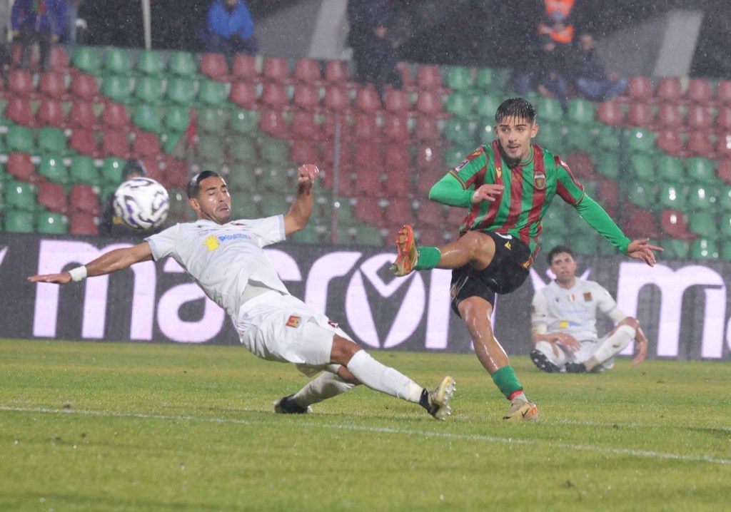 Un giocatore della Ternana calcia il pallone mentre un avversario del Livorno scivola per cercare di fermarlo, durante una partita di calcio sotto la pioggia.