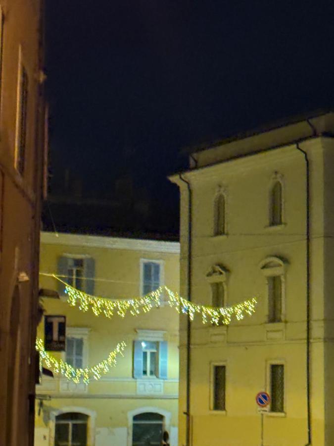 Vista notturna di una via con luminarie decorative appese tra gli edifici.