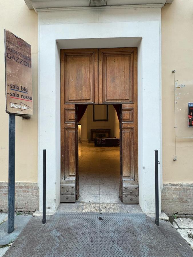 Entrance of 'Auditorium Gazzoli' featuring large wooden double doors, with a view of the interior space and signage indicating 'sala blu' and 'sala rossa'.