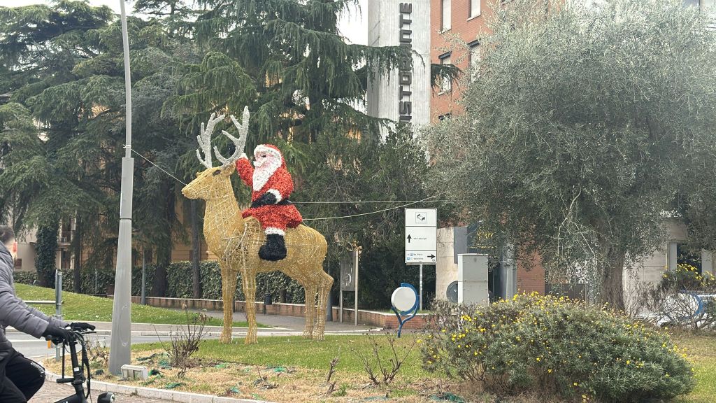 A decorative display featuring Santa Claus riding a reindeer, located in an outdoor setting with trees and signage in the background.