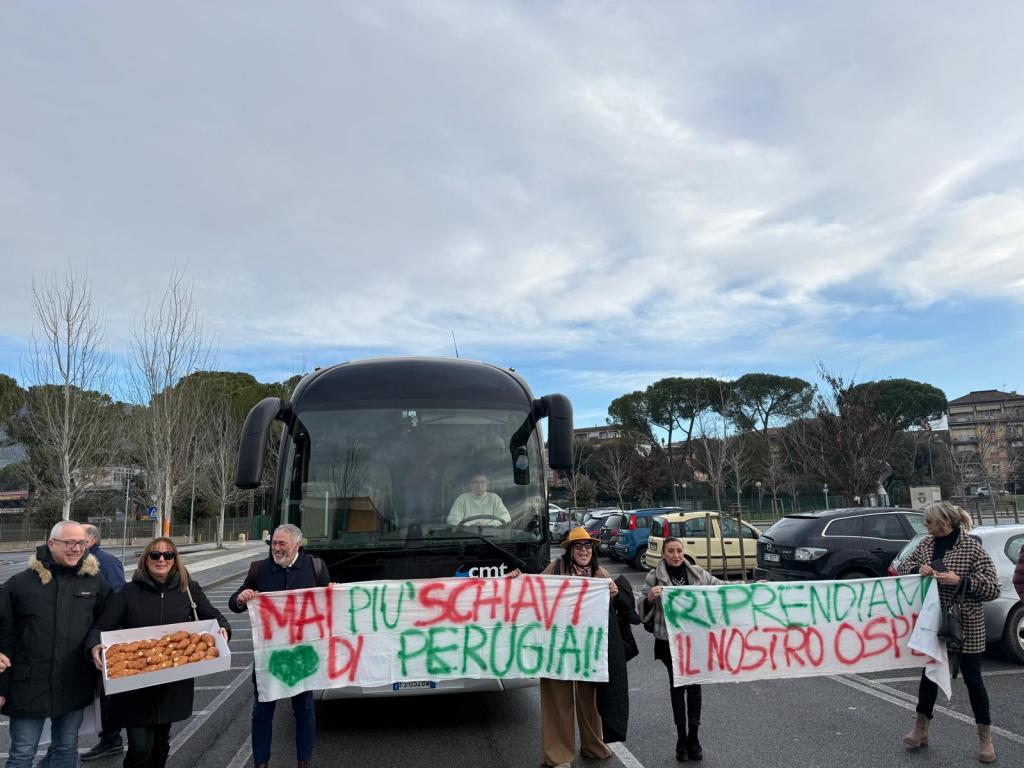 A group of people holding banners in front of a bus, advocating for their cause in a public space.
