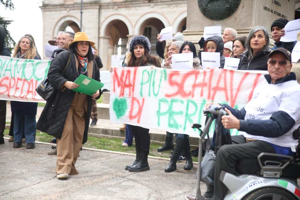 A group of protesters holding signs and banners, advocating for rights, with a focus on messages about freedom and rights, gathered in a public space.