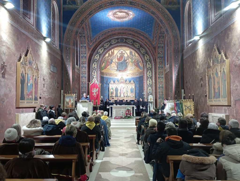 A group of people seated in a church during a ceremony, with religious icons and a decorated altar in the background.