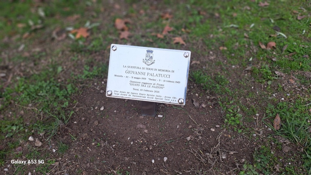 A memorial plaque dedicated to Giovanni Palatucci, located on a grassy area. The plaque includes details about his life and contributions.