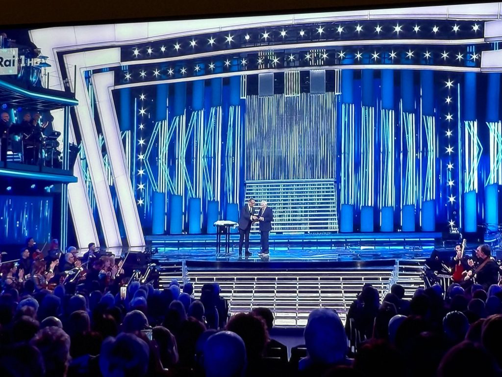 A stage set with bright blue lighting and a large audience watching a performance or event.