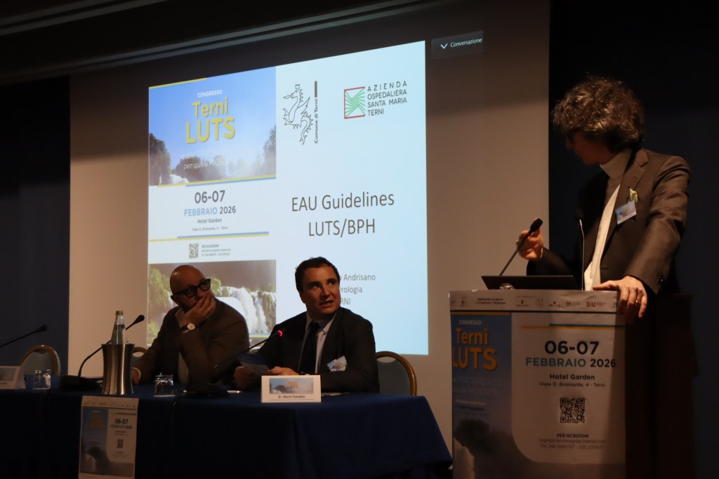 A conference scene featuring speakers at a panel discussion on LUTS/BPH guidelines, with a backdrop displaying event details including the date and venue.