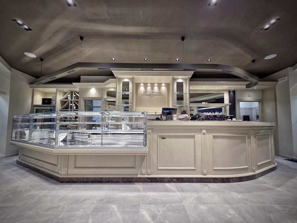 Interior view of a modern bakery or cafe with a sleek counter and display case, featuring elegant lighting and a contemporary design.