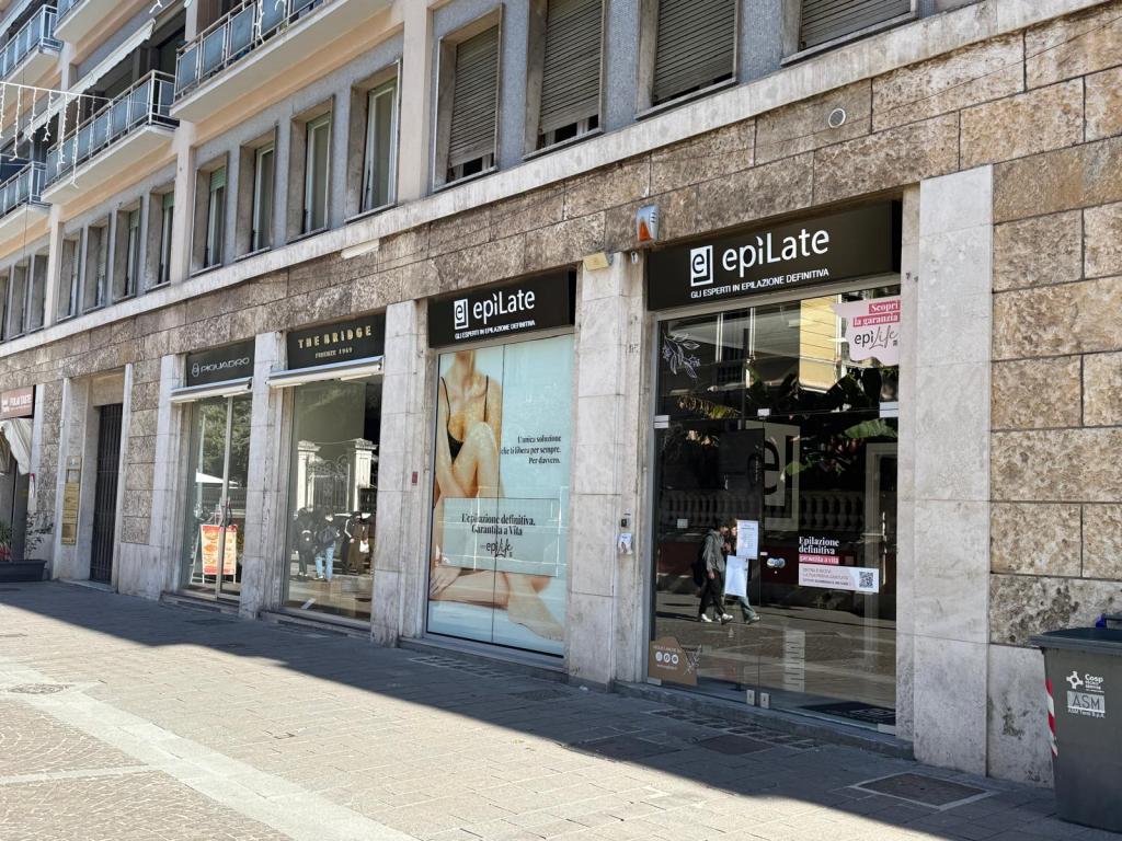 Exterior view of a beauty salon named 'epiLate' featuring a glass storefront and promotional signage.