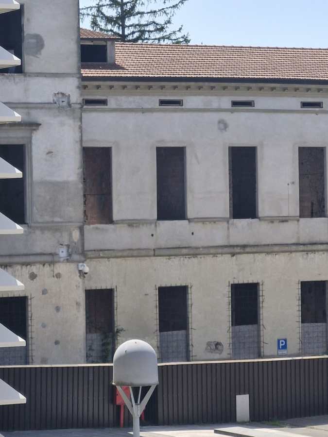 Abandoned building with boarded-up windows and a parking sign in the foreground.