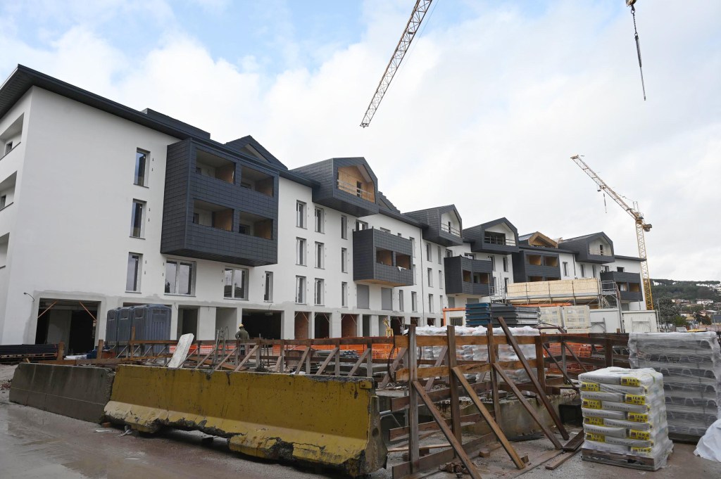 Construction site featuring a partially completed multi-story building with cranes and construction materials.