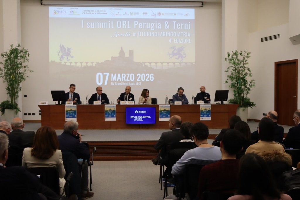 A conference setting featuring a panel of speakers at the I summit ORL Perugia & Terni, with a backdrop displaying the event date and venue details.