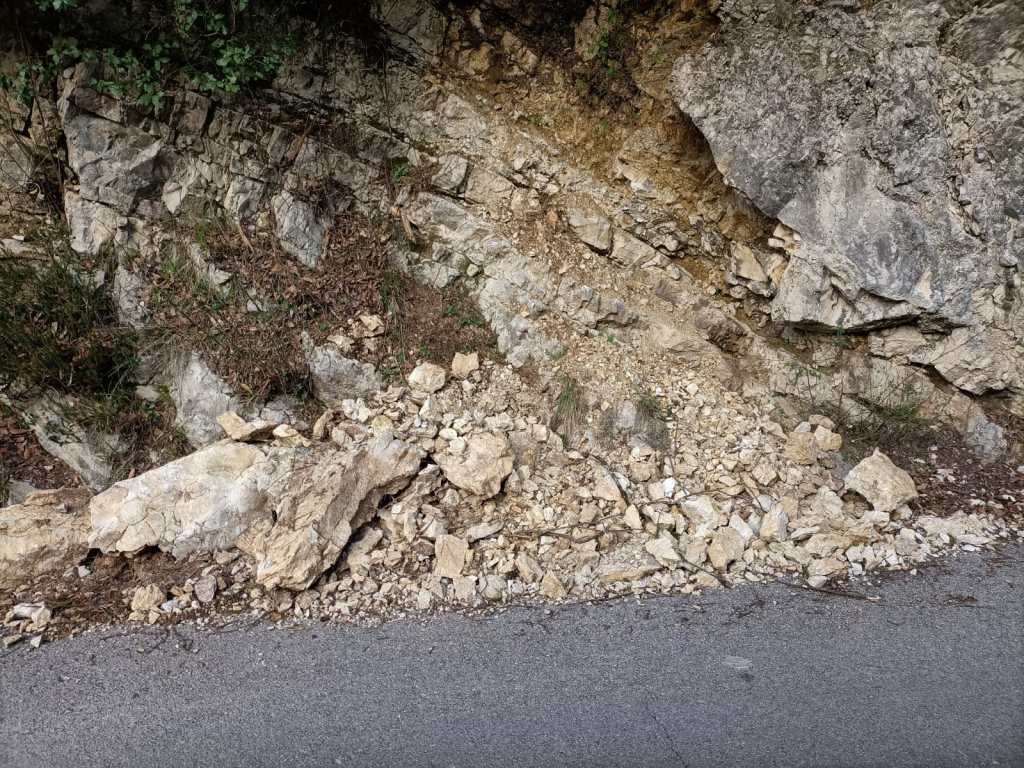 A rocky slope with loose debris and scattered stones next to a paved road.